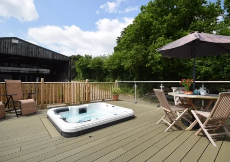 The decked patio, alfresco dining area & hot tub at The Owl Barn at Lower Langaton Farm, Chittlehampton
