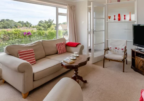The Pink Beach Bungalow, Paignton is a charming three-bedroom retreat with sweeping Torbay views, featuring a sunny tiered garden, comfortable coastal interiors, and Broadsands Beach less than a mile away for the perfect English Riviera escape.