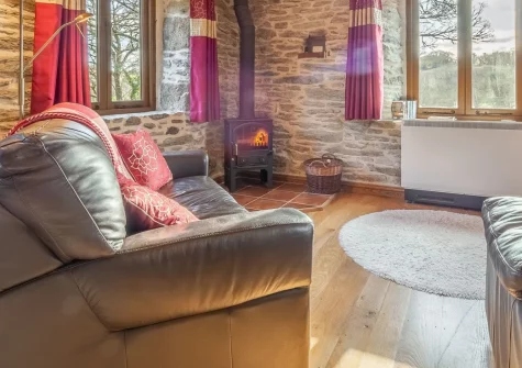 The Threshing Barn at Cusgarne Cottages is a beautifully renovated two-bedroom barn conversion in peaceful countryside, featuring vaulted ceilings with original beams, wood-burning stove, private terrace, and shared gardens with games room.