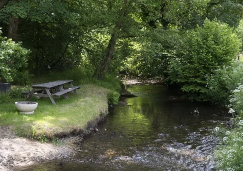 The picnic table by the river, with a firepit, is just one of many spots for you to enjoy