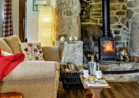Three Hares Cottage, Throwleigh is a characterful two-bedroom retreat nestled in peaceful countryside close to Dartmoor National Park, featuring exposed beams, twin wood burners, and a rustic Aga kitchen, with Dartmoor ponies grazing nearby.