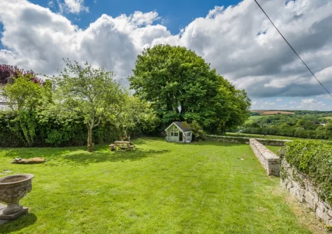 The shared rear garden, with children's playhouse, at Tregenna Farmhouse, Tredethy