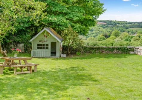 The shared rear garden, with children's playhouse, at Tregenna Farmhouse, Tredethy