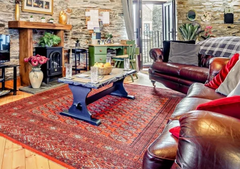 Trewint Round House, Menheniot is a charming reverse-level cottage set within peaceful farm grounds near Cornwall's south coast, featuring exposed beams, original stonework, beautiful countryside views, and warm farmhouse hospitality.