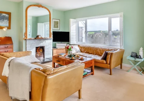 Two Stiles, St Merryn is a welcoming three-bedroom country retreat in peaceful North Cornwall, featuring far-reaching countryside and sea views from an upside-down layout, two cosy lounges with fires, and easy access to beautiful sandy beaches.