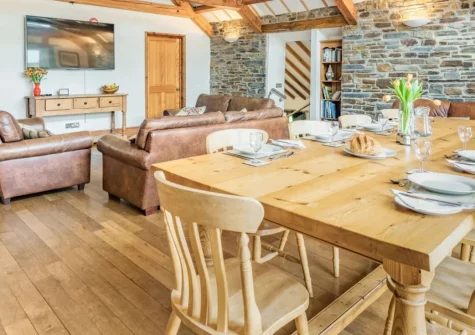 Wagon Linney, Lewdown is a beautifully converted barn on a 450-acre Devon farm, sleeping 10 guests across five bedrooms, featuring a games room with valley views, cosy snug with wood burner, and access to 74 acres of wildlife-rich woodland.