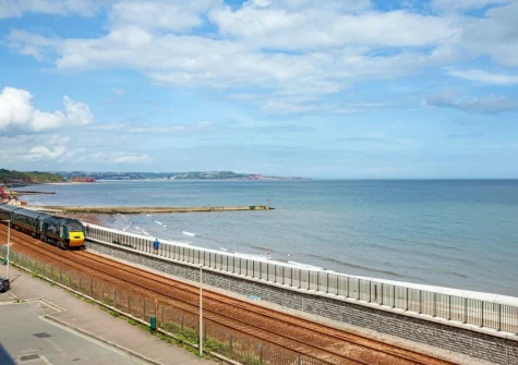 Dawlish seafront is a traditional, picturesque Devon coastal spot featuring a sandy beach, iconic red sandstone cliffs, and a unique, dramatic railway line running directly along the sea wall