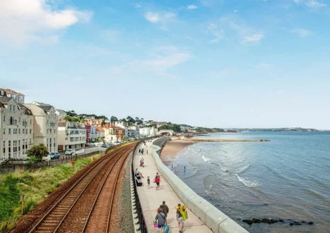 Dawlish seafront is a traditional, picturesque Devon coastal spot featuring a sandy beach, iconic red sandstone cliffs, and a unique, dramatic railway line running directly along the sea wall