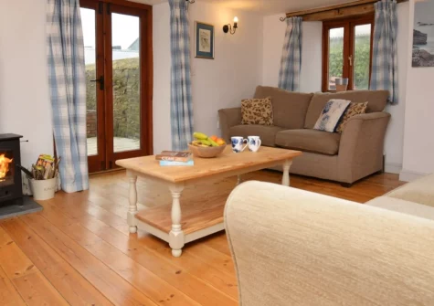 Welcombe Cottage, Gooseham is a cosy two-bedroom former workshop conversion set on a 267-acre North Cornwall dairy farm, featuring a wood burner, private patio, play barn, dog field and easy access to Bude's sandy beaches and coastal walks.