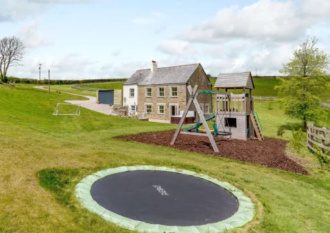 The large lawned garden with children's play area at West Park, Herodsfoot