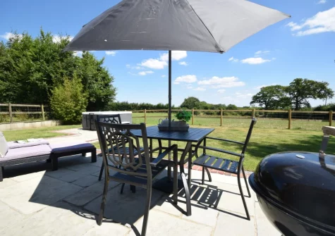 The patio, barbecue, alfresco dining area, hot tub & enclosed garden at Weston Farm Barn, East Knowstone