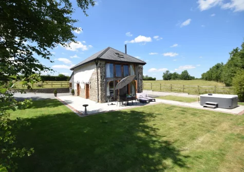 The patio, barbecue, alfresco dining area, hot tub & enclosed garden at Weston Farm Barn, East Knowstone