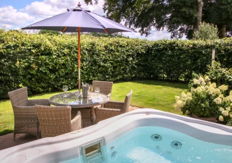 The patio, alfresco dining area, hot tub & enclosed garden at Wrens Thatch, Ebberley